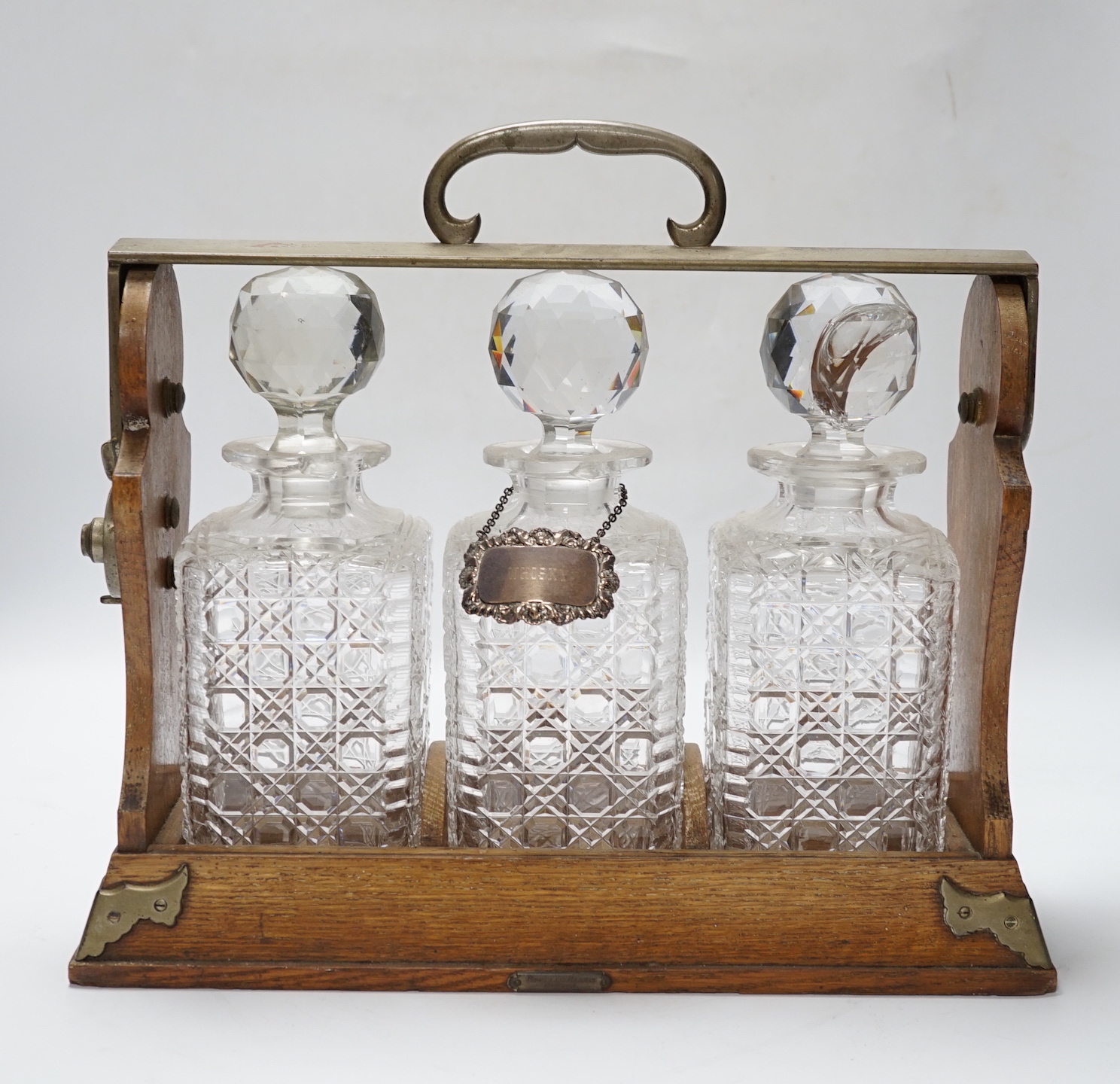 A silver-plated three-bottle oak tantalus, 32cm